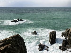 絶壁と日差しがあたってグリーンに輝く日本海